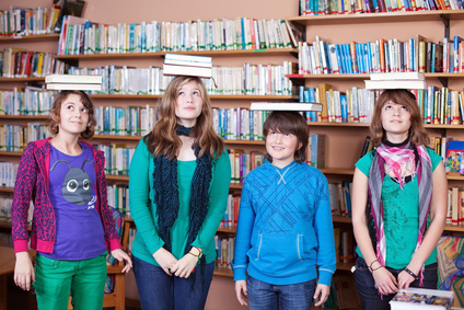 Vier Kinder mit Büchern auf dem Kopf