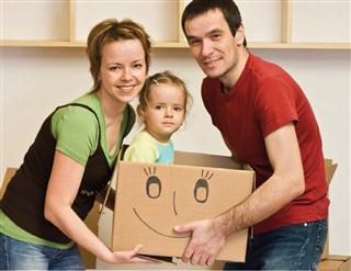 Eltern tragen ein Kind in einem Umzugskarton